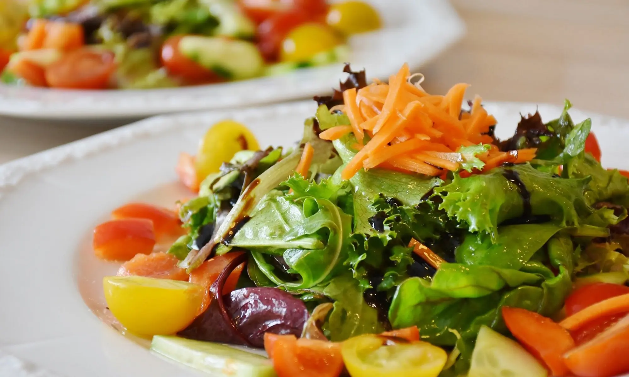 Fresh mixed greens salad with cherry tomatoes, carrots, and balsamic glaze at Happy Sushi Japanese restaurant in Santa Clara